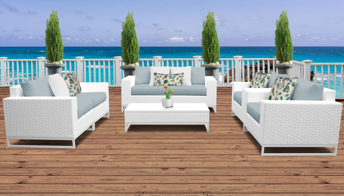 White wicker patio furniture with cilantro green cushions sits on a beautiful wood patio, perfect for Labor Day parties!