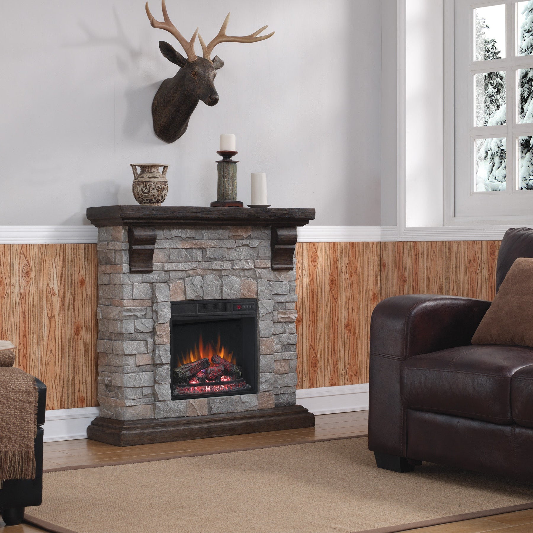 Living room with stone fireplace, leather sofa, and deer head mount.